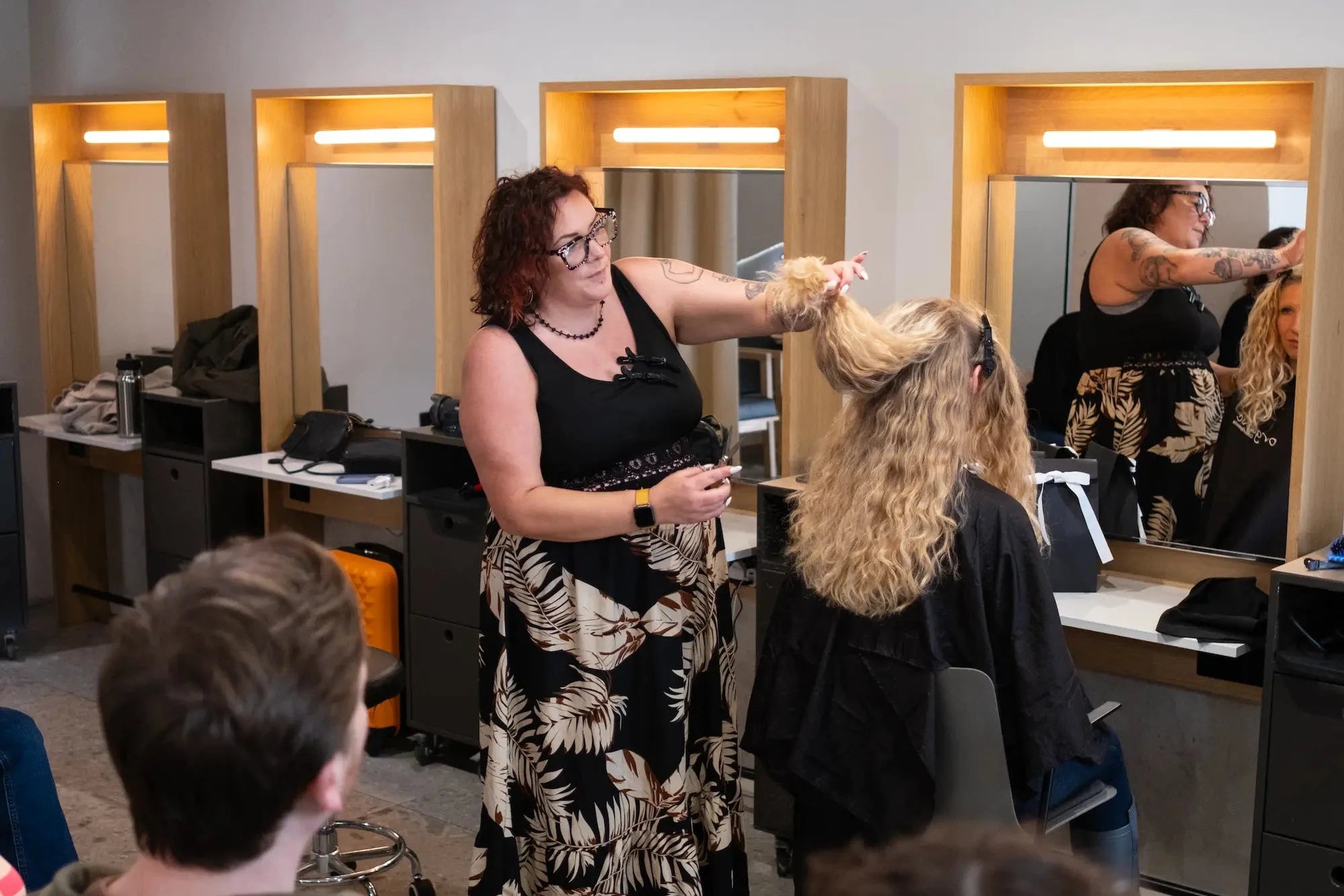 Client getting her curly hair styled in a salon with mirrors and chairs by OCS Ambassador, Jen Gaia.